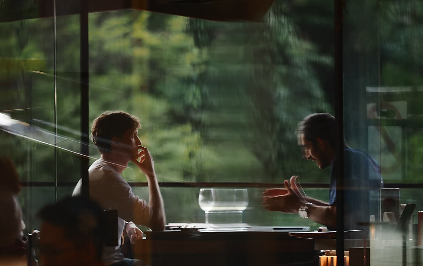 Two people at a table, one explaining something with their hands.